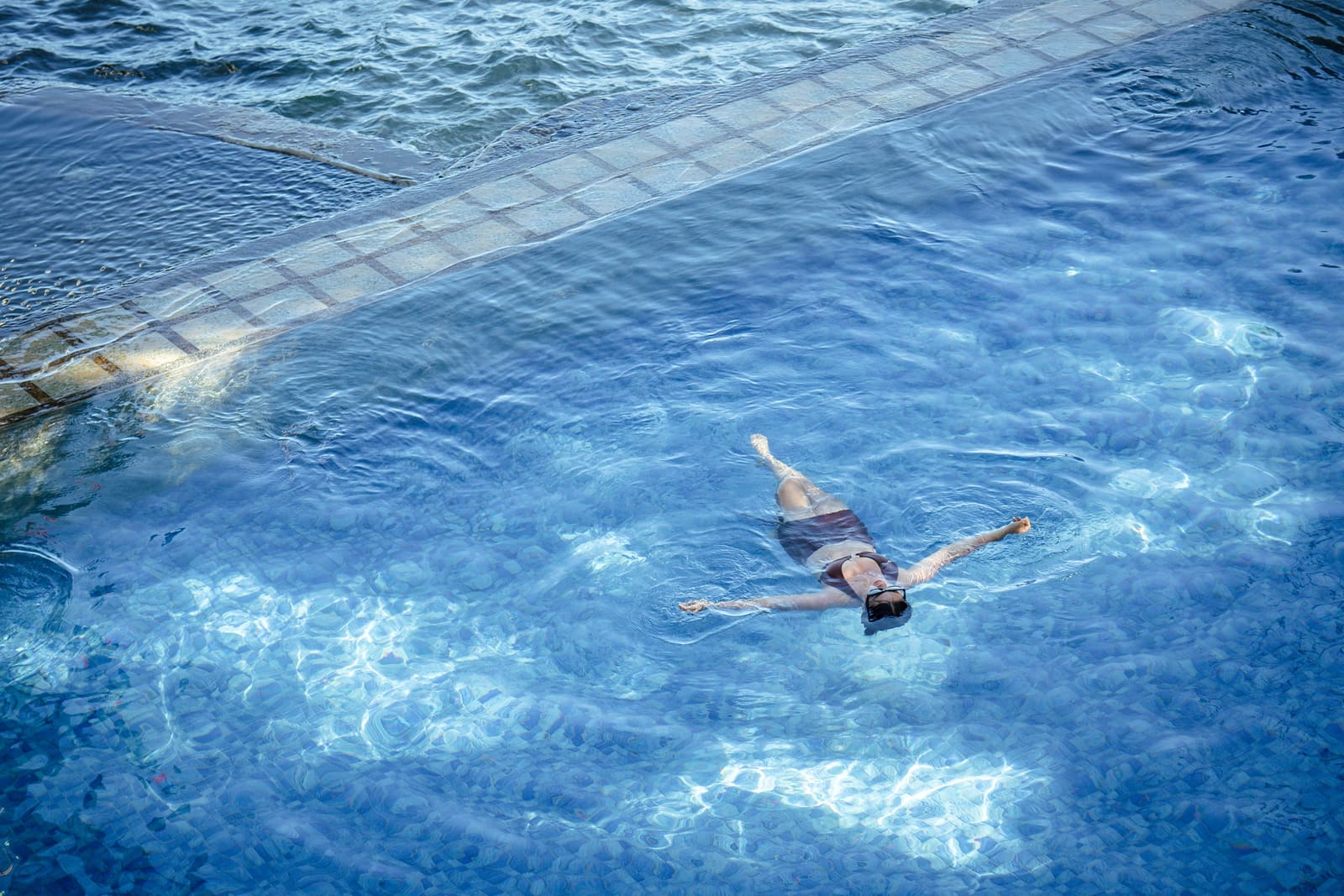 Guest floating in the clear blue pool at Isola Vista Beach Resort